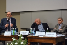 Prof. Jacek Raciborski przemawia siedząc w prezydium. Obok Niego siedzi prof. Kazimierz Friske i prof. Henryk Domański.