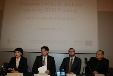 Osoby prowadzące konferencje siedza przy stole za nimi wyświetlana jest prezentacja