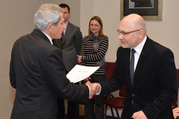 prof. Władysław Stępniak wręcza dyplom uczestnikowi szkolenia. W tle widać pozostałych uczestników.