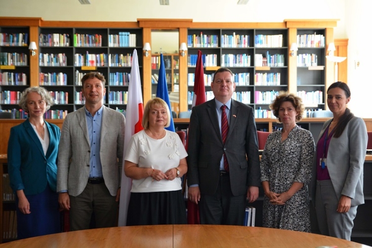 zdjęcie grupowe uczestników spotkania na tle flag