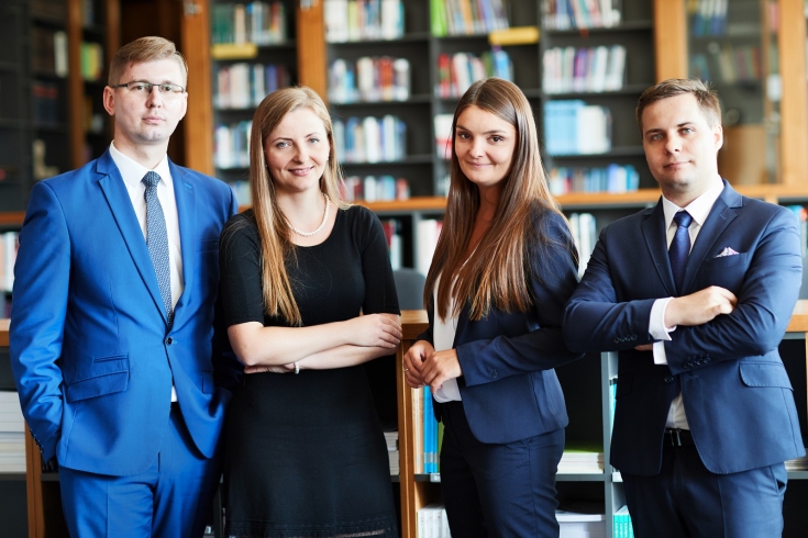 cztery osoby stoją w bibliotece KSAP